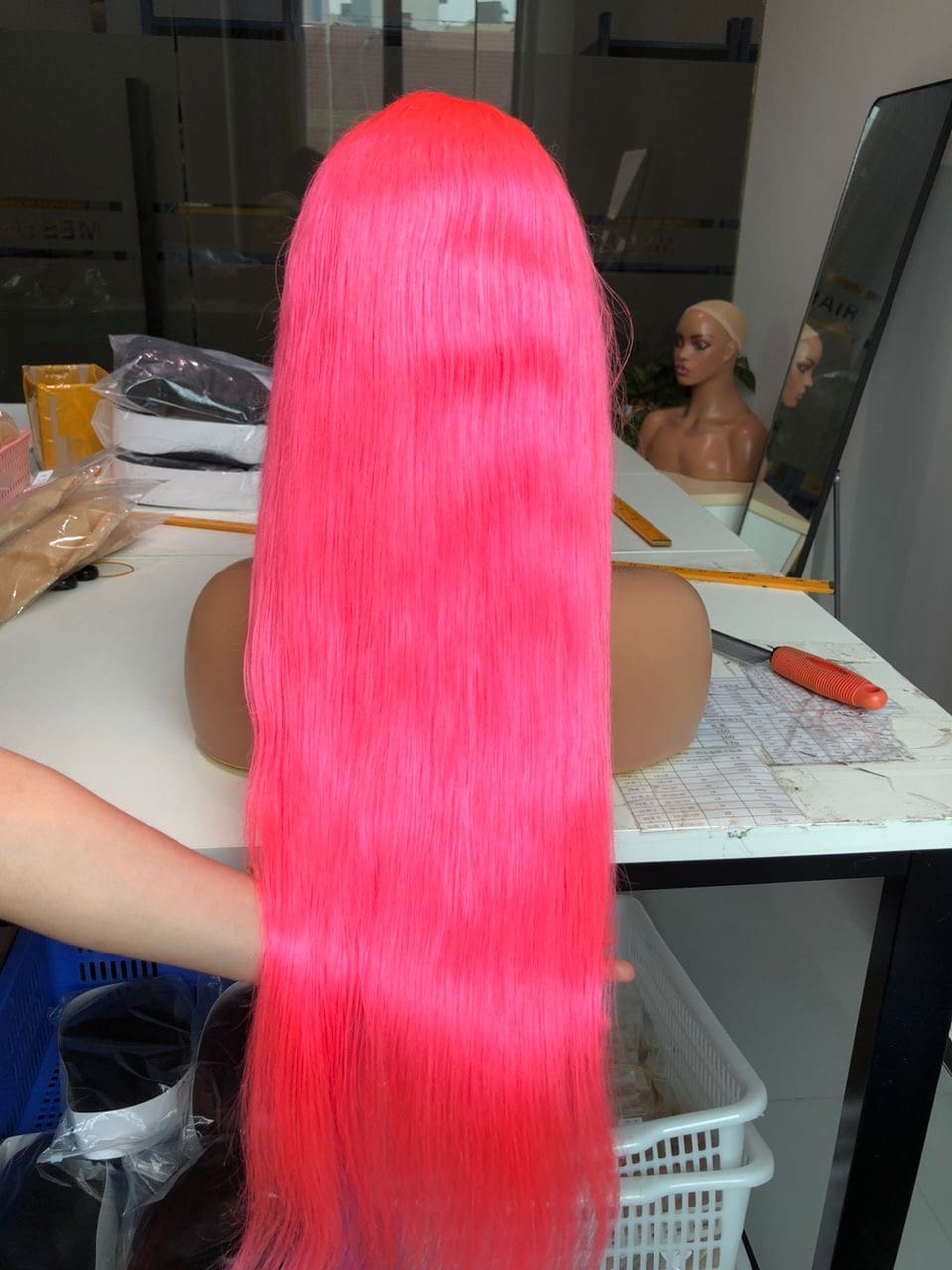 A woman with long pink hair sitting at a table.