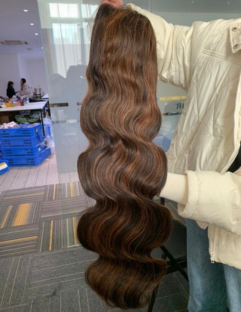 A woman holding a long brown hair extension.